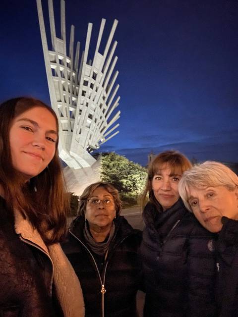       Four people posing with a modern statue.
  