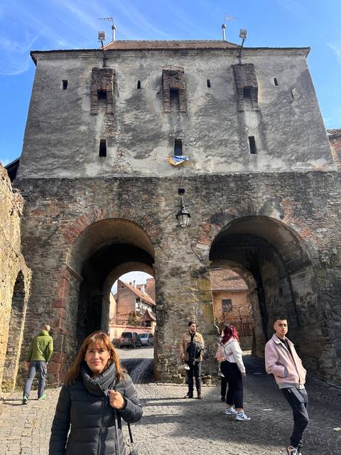       People standing near a historical wall with arches.
  