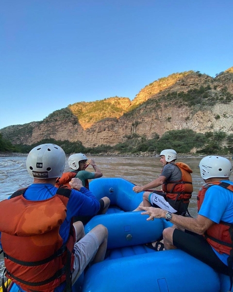       People rafting on a river with rocky cliffs surrounding.
  