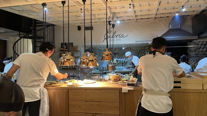       Restaurant kitchen with chefs preparing dishes.
  