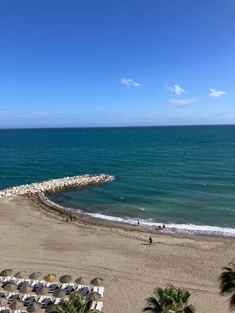       View of a beach with a calm sea and clear sky.
  