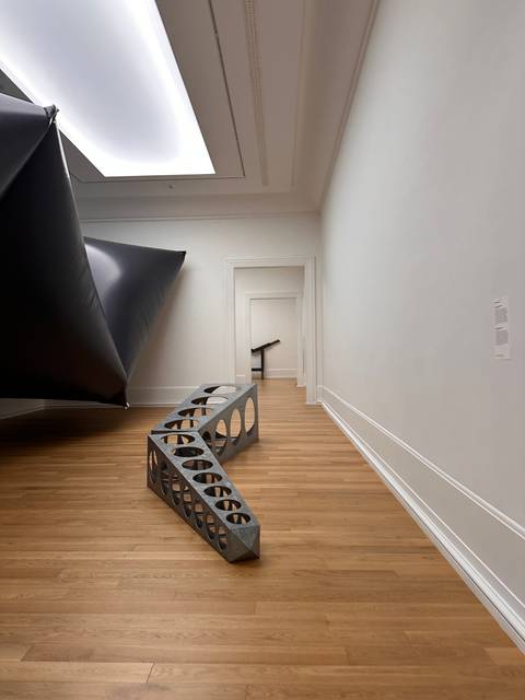       Modern interior with wooden floor and abstract sculpture.
  