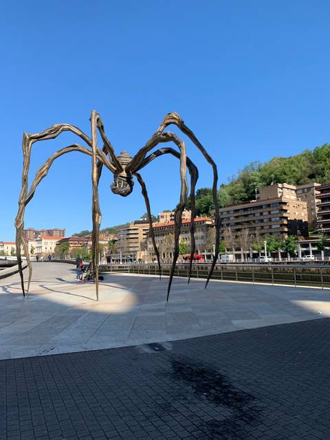       A large spider-like sculpture in an urban setting.
  