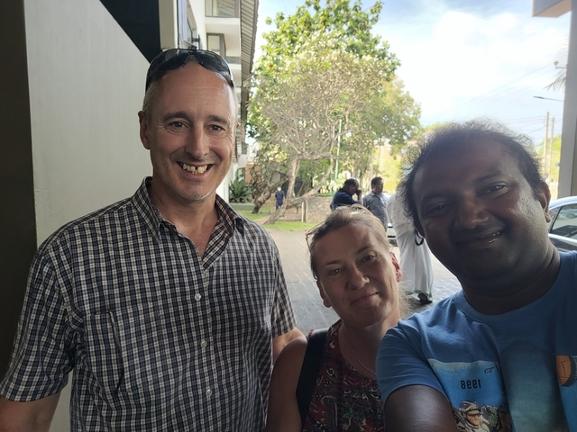       A group of people smiling for a photo in a garden area.
  