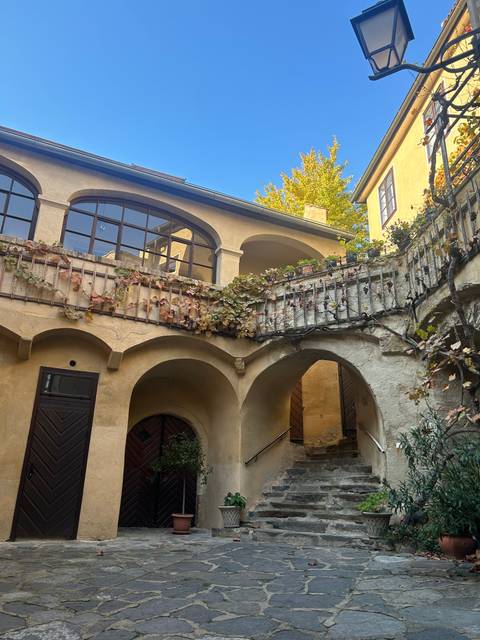       Building facade with arches and potted plants under a clear blue sky.
  