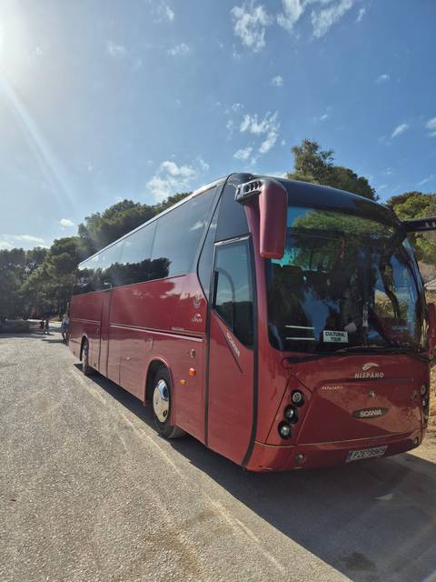       Large red tourist bus parked outdoors.
  