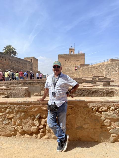 Person posing against a historical backdrop.