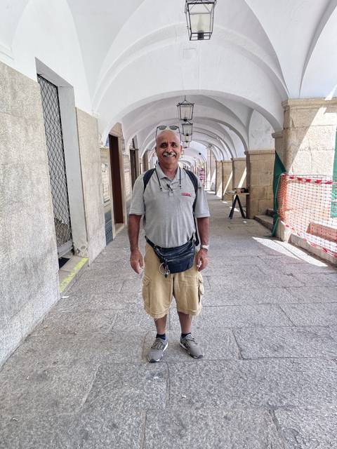 Person standing in an arcade with arched architecture.