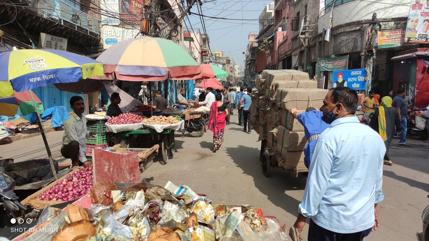       Busy market street with vendors and shoppers.
  