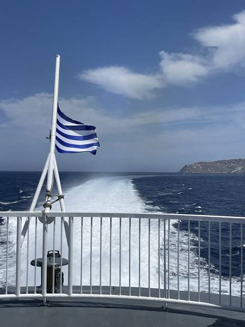       Blue and white frayed flag waving on a boat at sea.
  