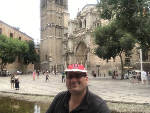 Upside-down selfie of a man with a large cathedral in the background.