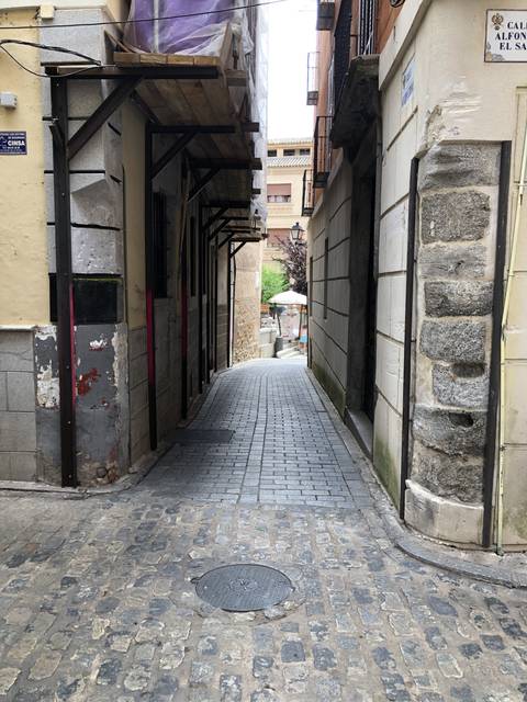 Narrow alley with stone pavement and buildings.