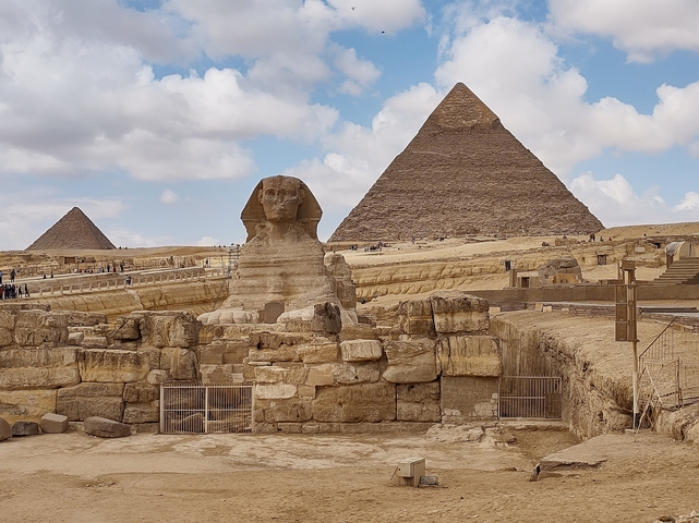       Iconic Sphinx and pyramids at Giza under a blue sky.
  