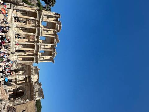       Ancient ruins with a crowd of people under a clear blue sky.
  