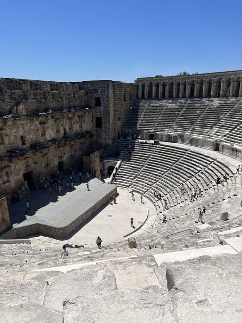       Ruins of an ancient amphitheater with visitors.
  