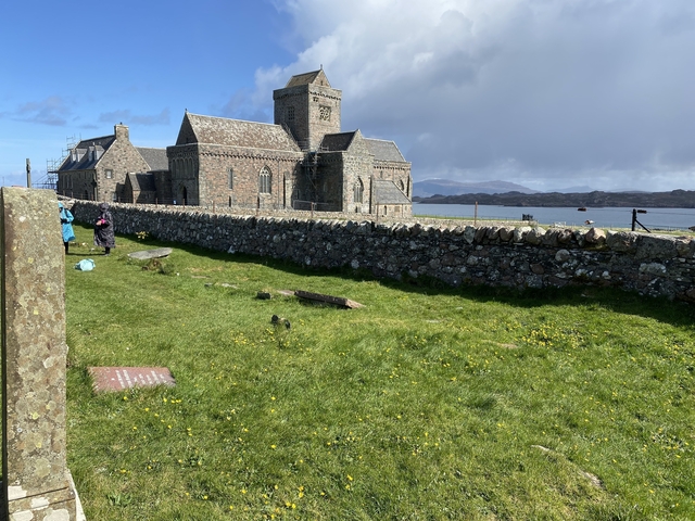 Historic building and stone wall by a lake.