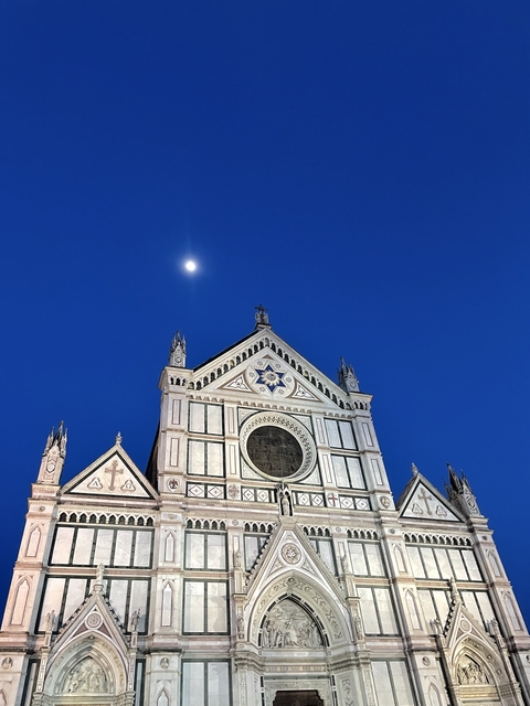 A grand church facade under a twilight sky with the moon.