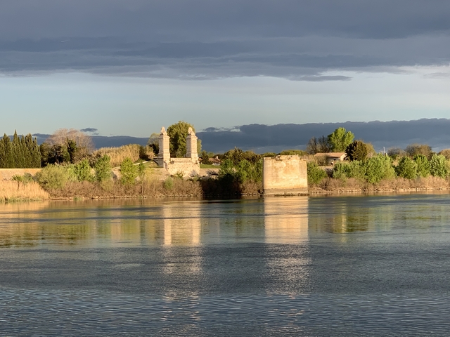 Riverside view with ancient stone structures and trees.