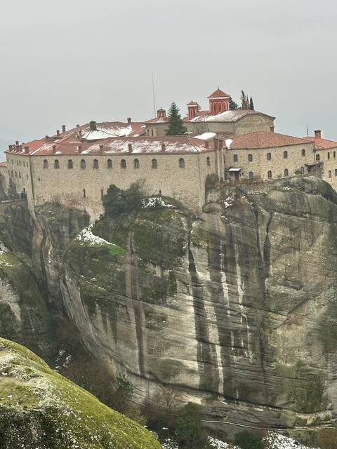 Monastery on top of a rocky cliff with snow.