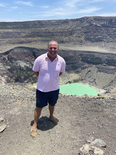       Man standing at the edge of a volcanic crater lake.
  