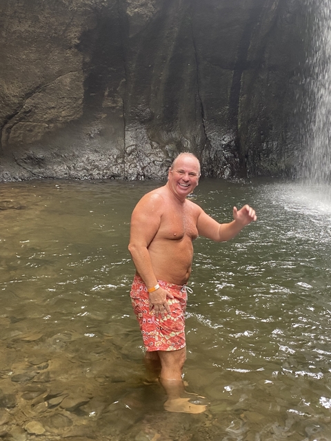       Person standing by a waterfall smiling.
  