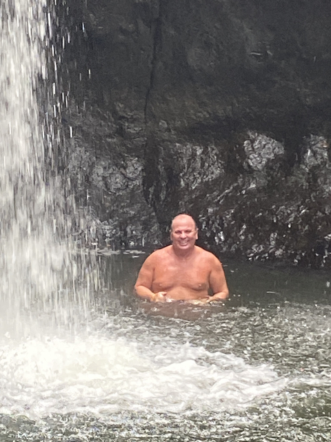       Person enjoying a waterfall pool.
  
