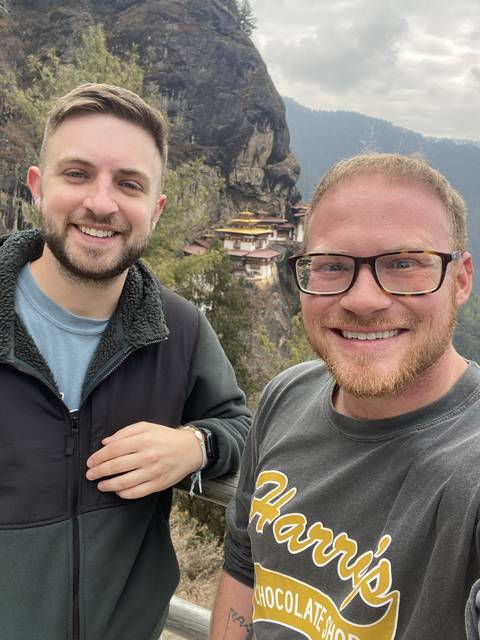 Two people taking a selfie with a mountainous backdrop.