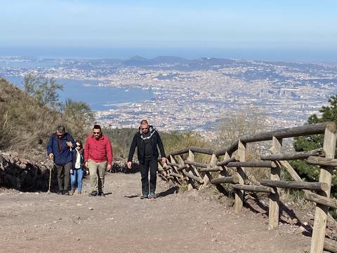       People hiking on a trail with a view of the Bay of Naples.
  