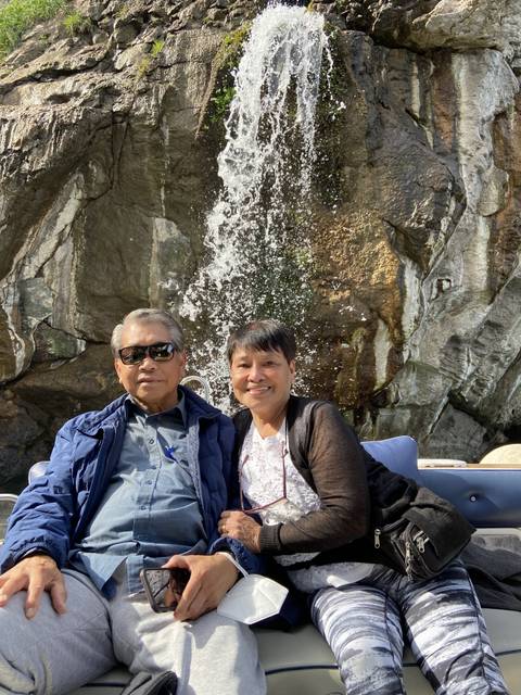       Couple sitting near a waterfall with rocky backdrop.
  