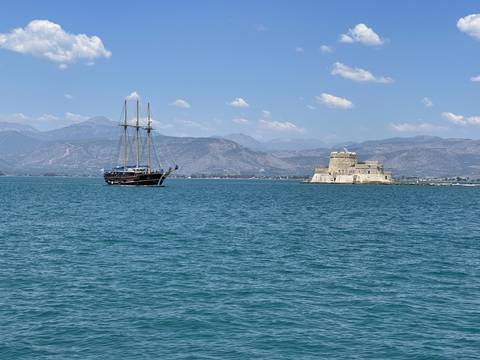 Upside-down view of a coastal castle and a ship on the water.