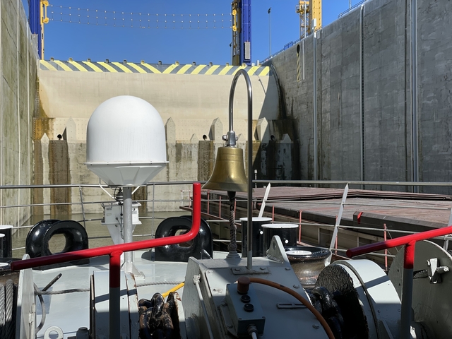       A close-up view of a ship's deck with a bell and equipment.
  