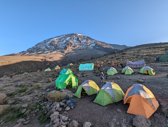       Campsite with colorful tents and a mountain in the background.
  