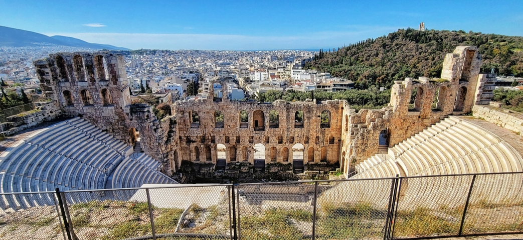 Ancient amphitheater ruins with a cityscape in the background.