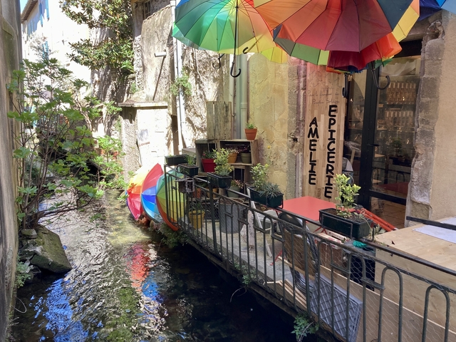 Quaint outdoor cafe alongside a narrow stream in a village.