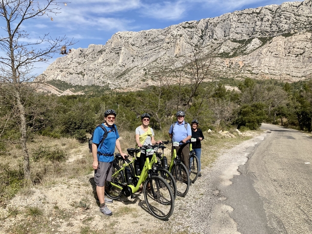       Group of cyclists posing with bicycles against a backdrop of rocky hills.
  