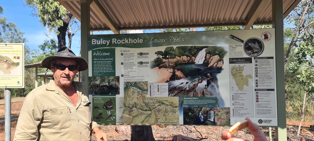 Man standing beside an informational map sign about Buley Rockhole.