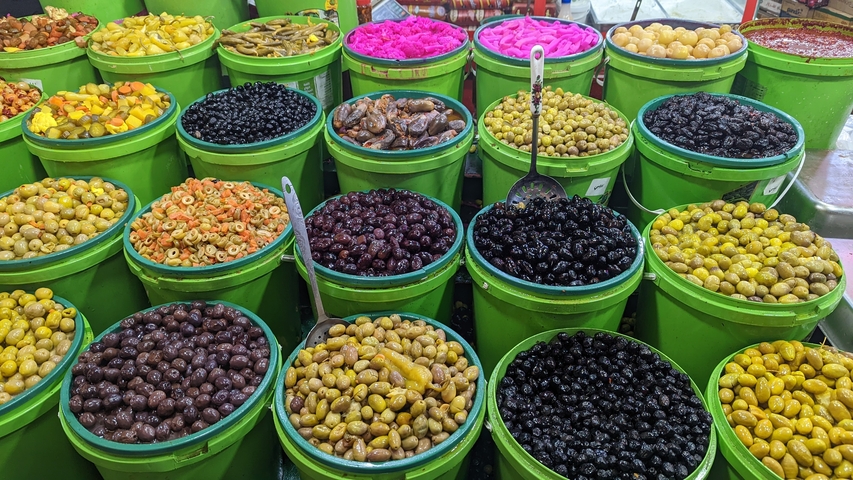 Variety of pickled foods displayed in large green containers.
