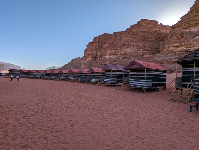       Row of traditional huts against a backdrop of rocky terrain.
  
