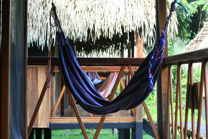       Colorful hammocks hanging in a thatched-roof veranda.
  