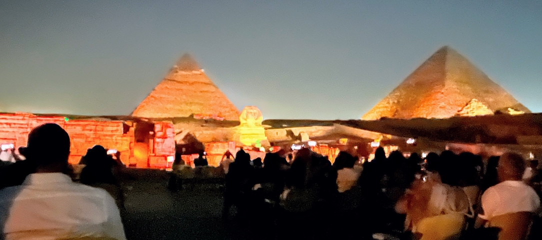 Nighttime show with pyramids illuminated in the background