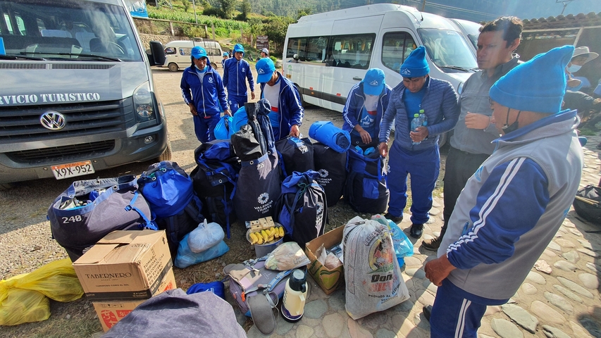 Group of people in blue uniforms preparing for a trekking journey.