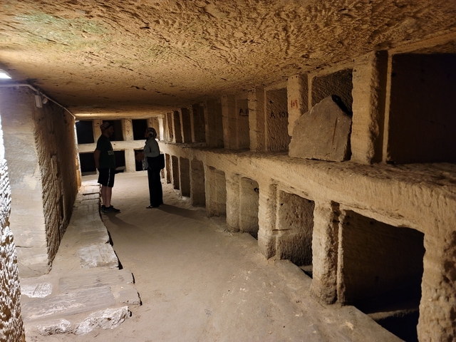 People exploring an ancient subterranean hallway.