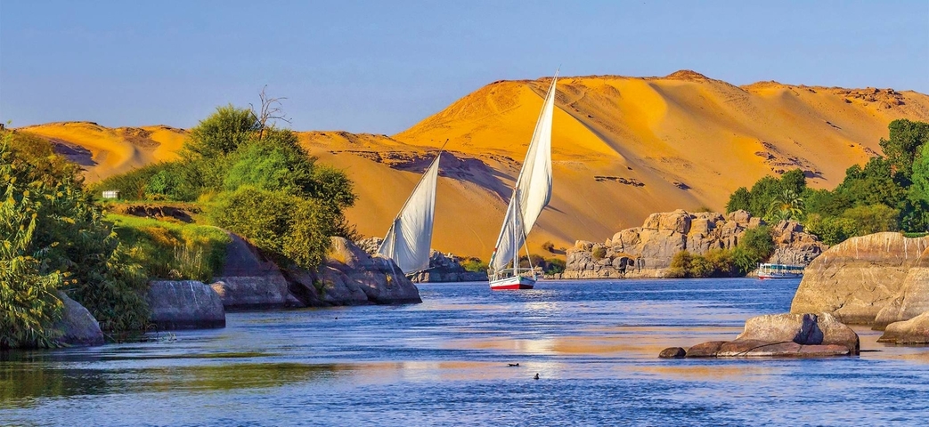 Scenic view of the River Nile with sailing boats, surrounded by desert and rocks.