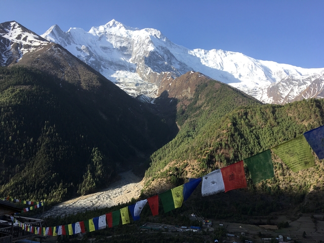 Mountains with snow and colorful prayer flags in the foreground.