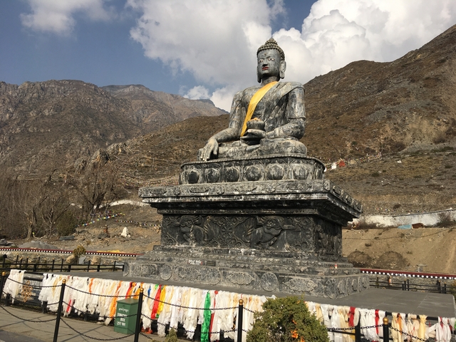 Large Buddha statue in a mountainous landscape.