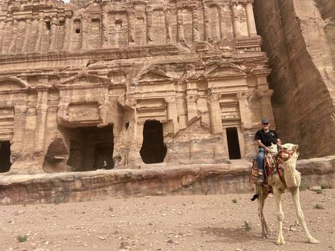       Camel rider in front of Petra's rock-cut architecture.
  