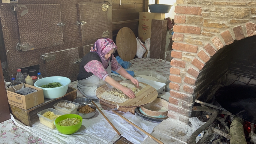 Woman preparing traditional Turkish food in a rustic kitchen setting.
