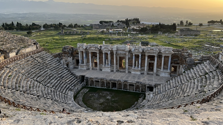 Ancient amphitheater with exposed stone seating and stage.