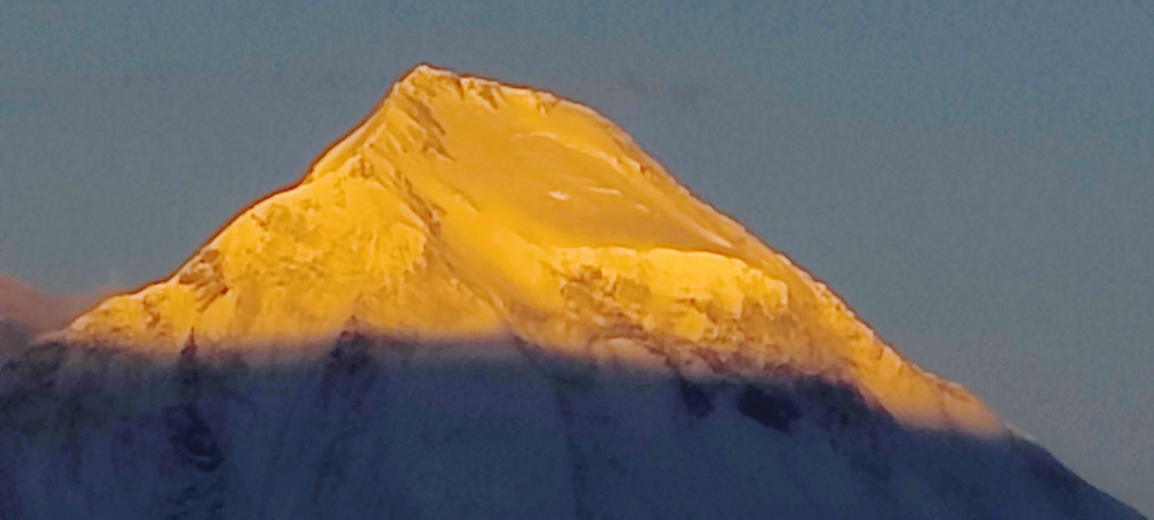 Golden-lit mountain peak possibly during sunrise or sunset.