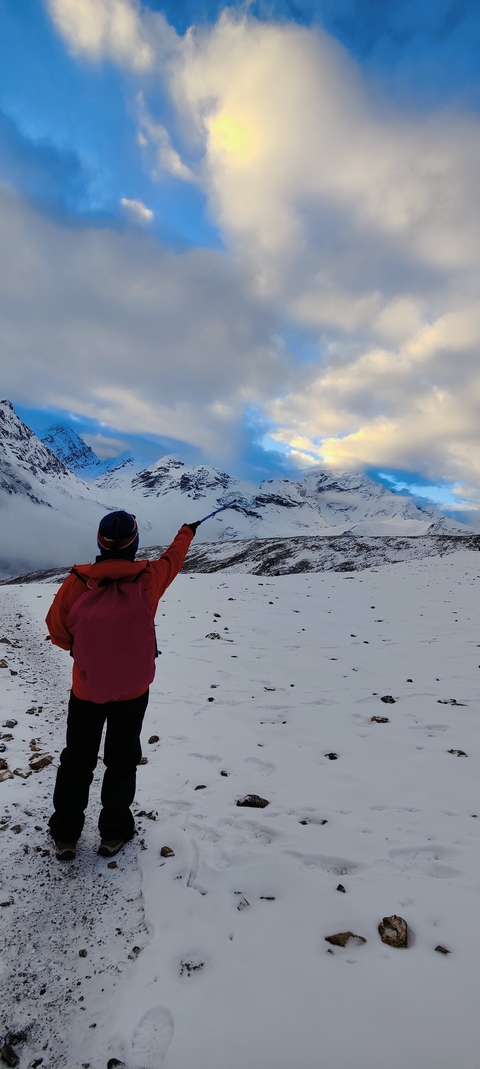 Person pointing towards snow-covered mountains in a breathtaking landscape.